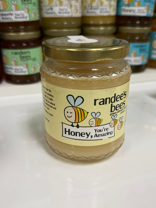 Jar of honey with a smiley bee design on a white surface