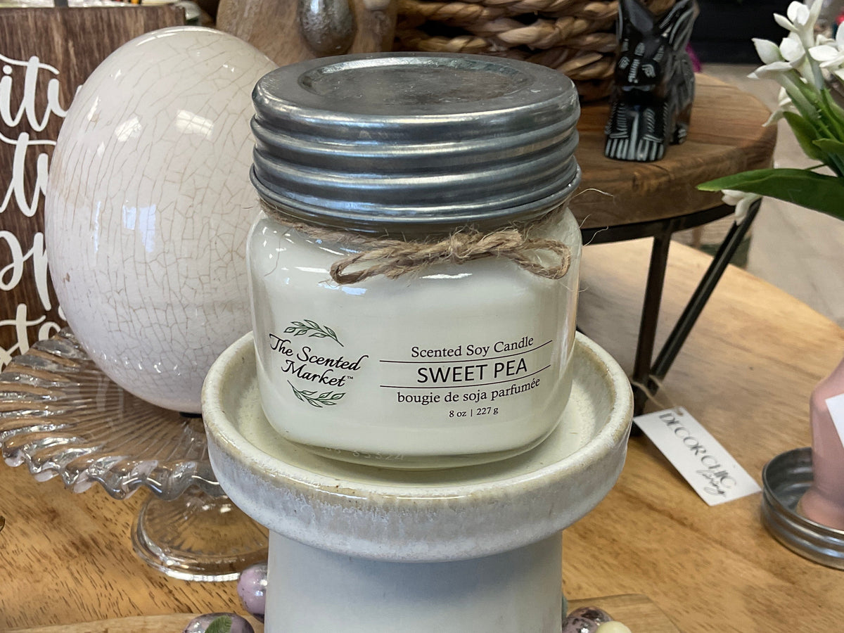 Scented soy candle in a mason jar on a decorative stand with a blurred background