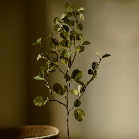 Artificial plant branch with green leaves on a blurred background