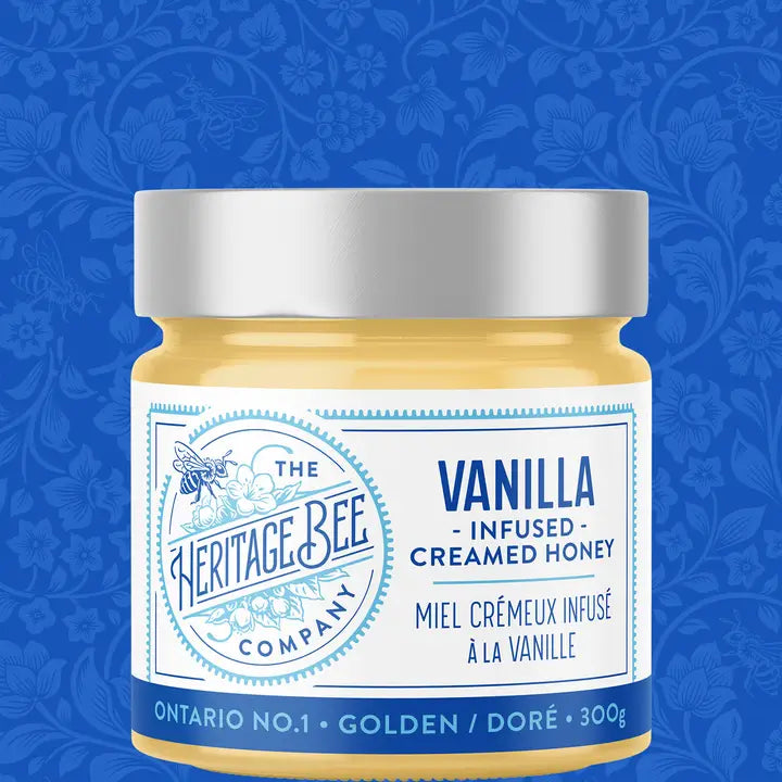 Jar of Vanilla Infused Creamed Honey from The Heritage Bee Company on a blue floral patterned background