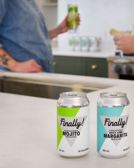 Two cans of 'Finally!' non-alcoholic mojito and spicy lime margarita on a kitchen counter.