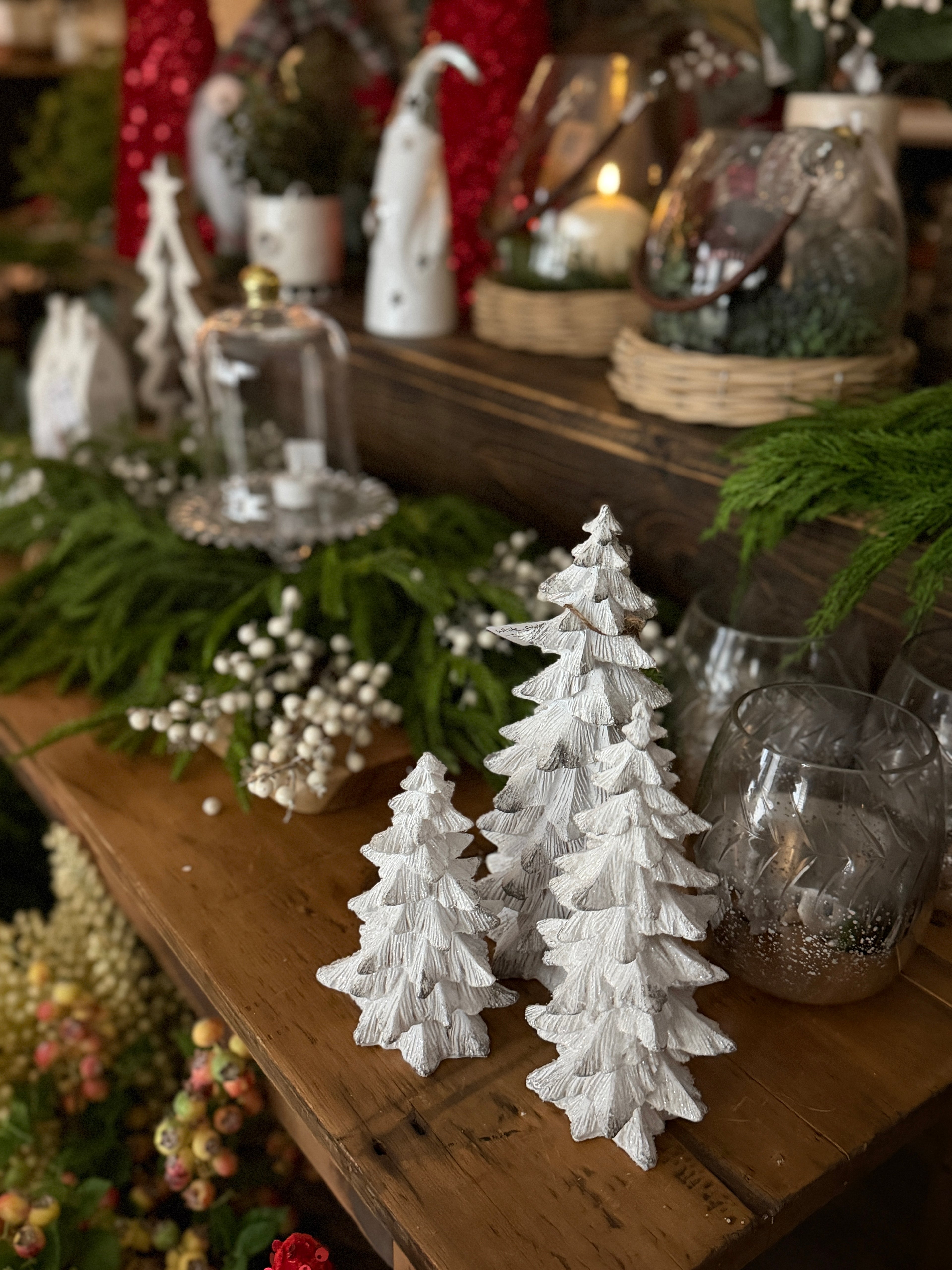Decorative white Christmas trees on a wooden table with festive background