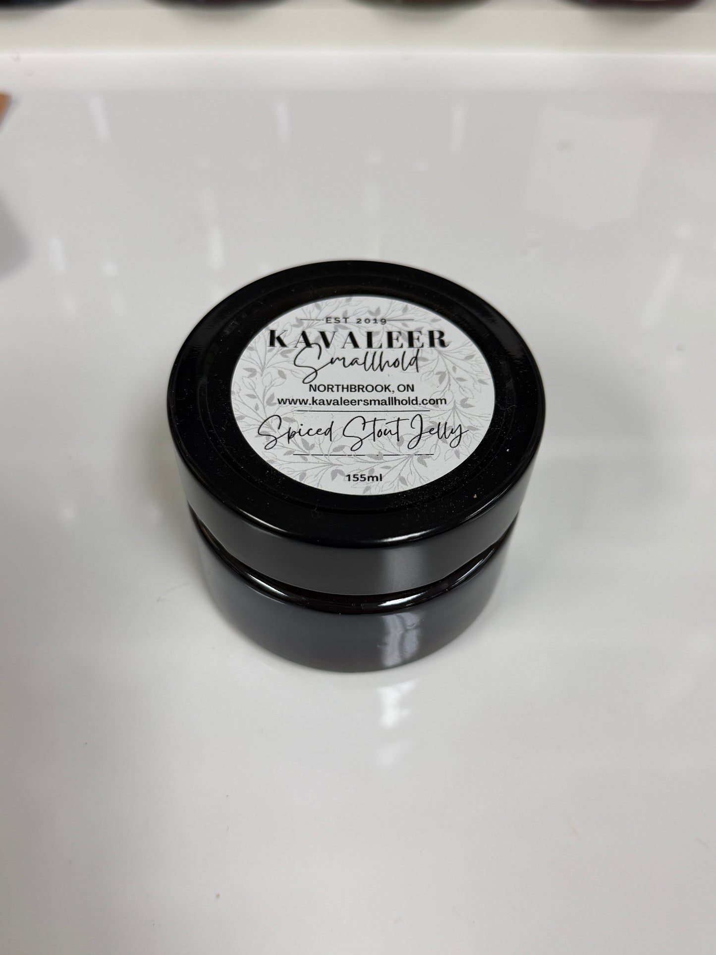 Black container of Kavaleer Spiced Stout Jelly with a white label on a white background