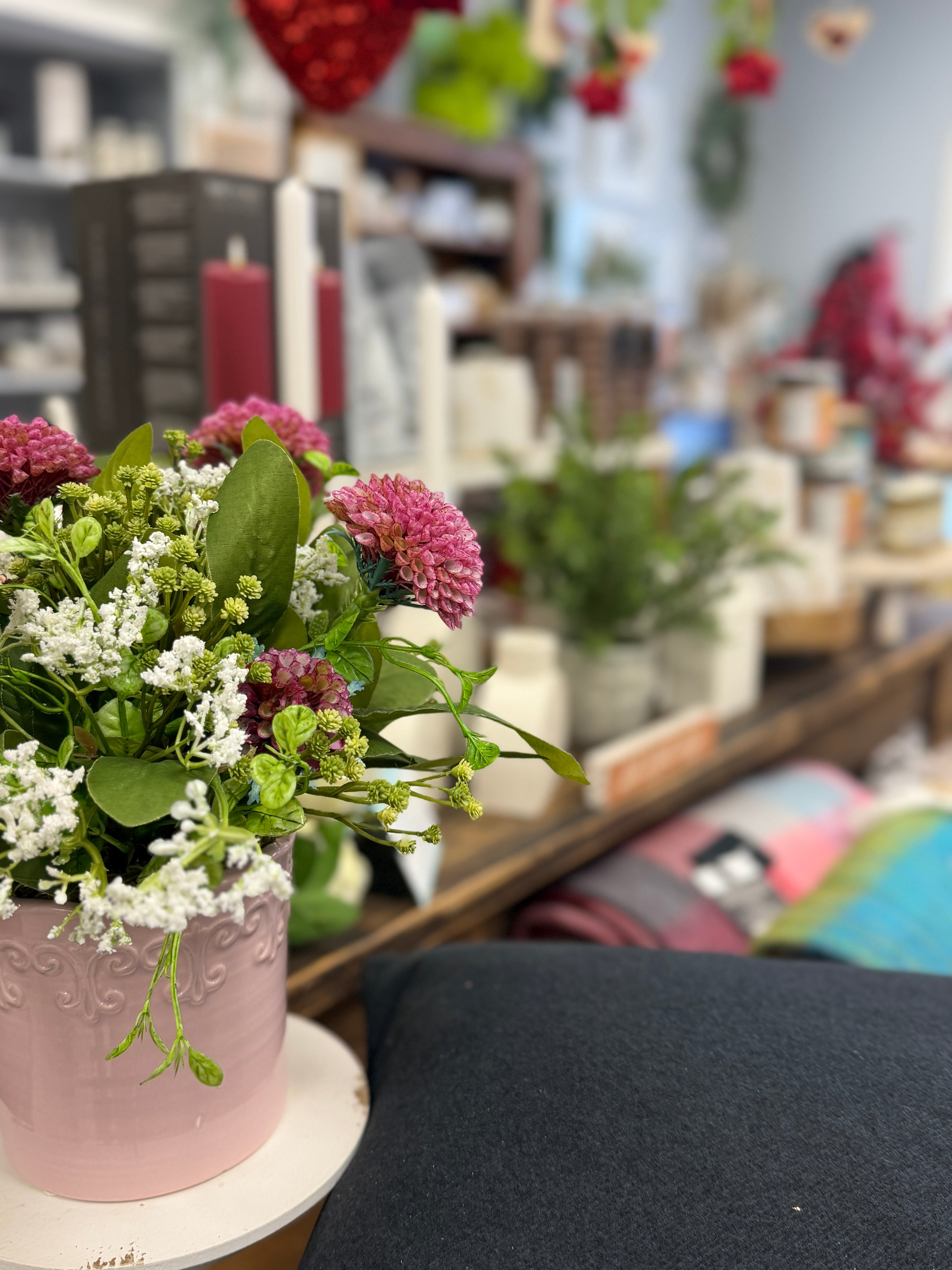 Pink vase with flowers on a table in a store setting