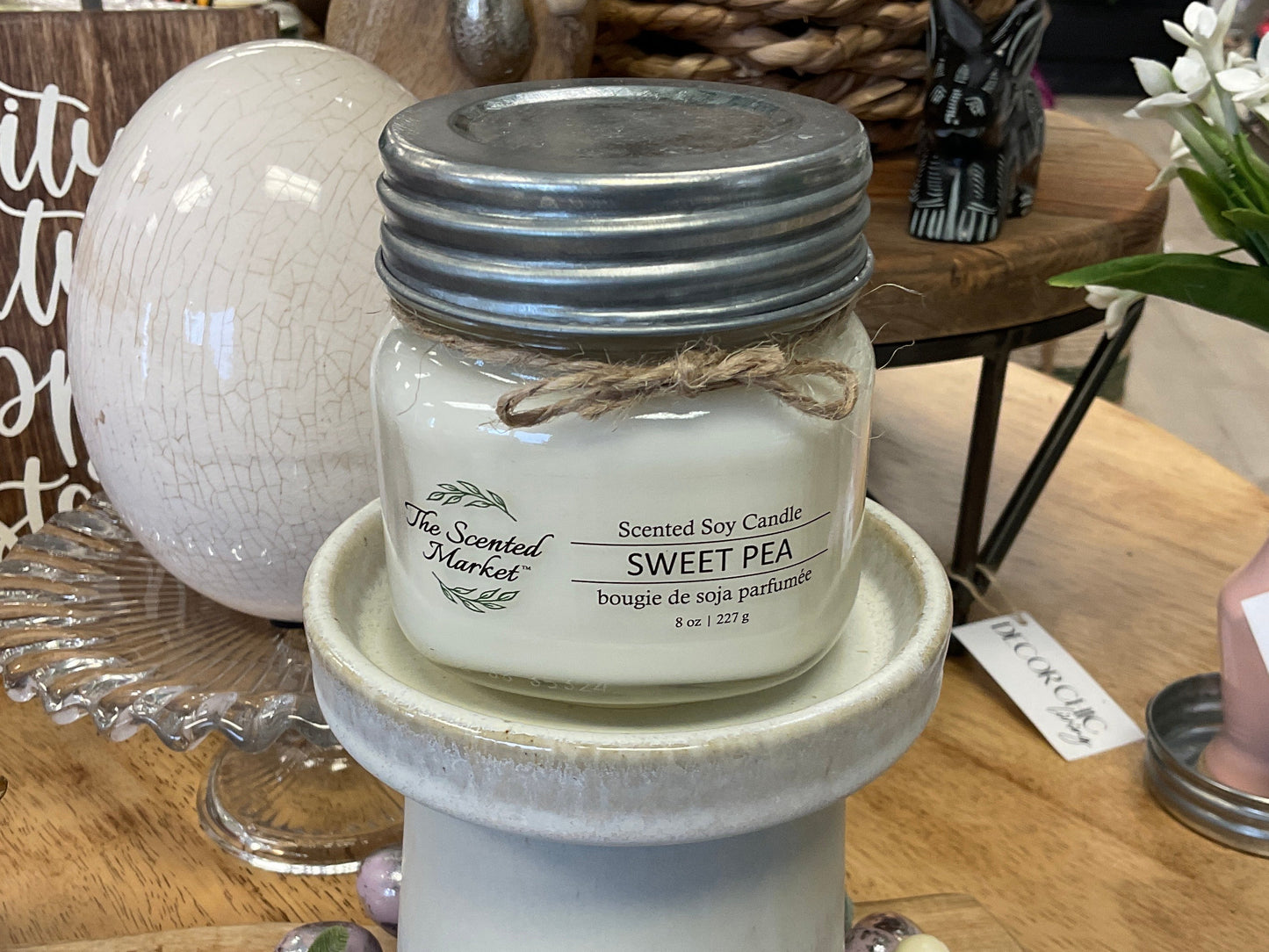 Scented soy candle in a mason jar on a decorative stand with a blurred background