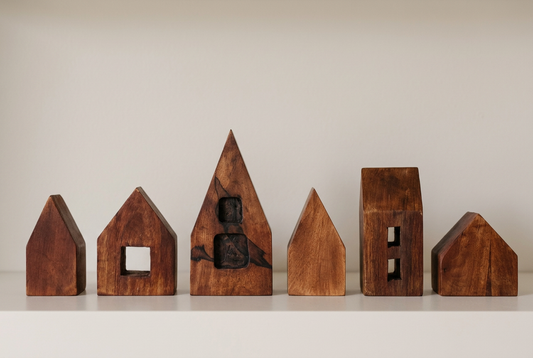 Six rustic wooden houses arranged in a bright, simple group photograph